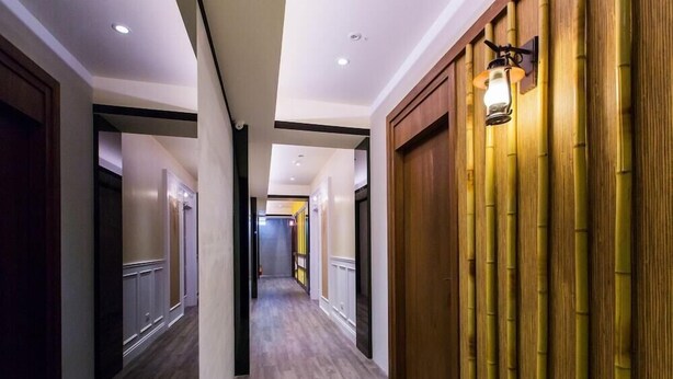 A hotel corridor with wooden doors, a bamboo wall, and recessed lighting. - Cloud Home (Luodong)
