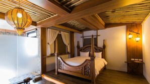 A bedroom with a wooden four-poster bed, a hanging lantern, and a small table with two lamps. - Cloud Home (Luodong)