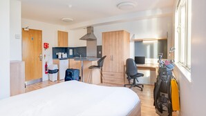 A compact hotel room with a bed, kitchenette, desk, and chair. - Cityheart Fort William- Campus Accommodation (Fort William)