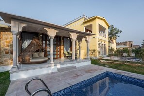 Zona junto a la piscina con un muro de piedra, una silla de mimbre y vista despejada del agua.