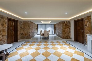 Una habitación con piso a cuadros, paredes de piedra y una mesa de comedor con sillas.