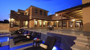 A pool area with lounge chairs and a covered patio with tables and chairs. - Juna Mahal Jungle Resort Ranthambore (Sawai Madhopur)