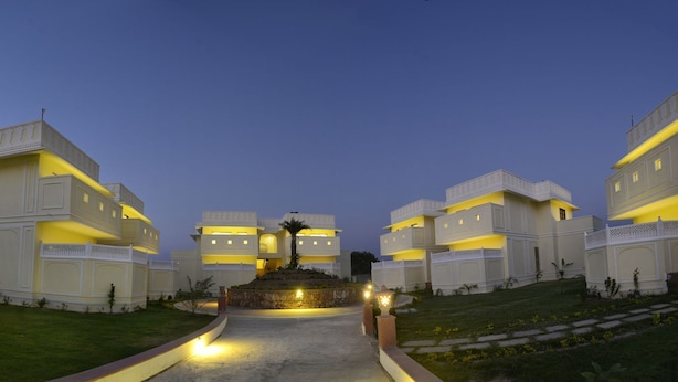 A multi-story hotel with a central courtyard, featuring a statue and a palm tree. - The Tigress Spa and Resort (Sawai Madhopur)