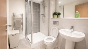 A bathroom with a shower, toilet, sink, and a towel rack. - City View Apartment w/ Balcony & Gym Access (Manchester)