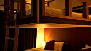 A bunk bed room with a wooden ladder, a bedside table with a lamp, and a wall with vertical stripes. - Hotel From Okinawa (Naha)