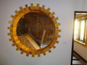 A circular wooden wall art piece with a central wooden structure, possibly a seating area, and a window on the right side. - Mai Chau Nature Lodge - Hostel (Mai Chau)