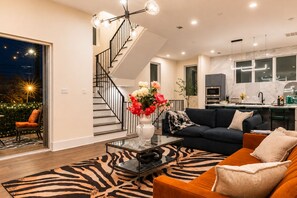 A modern living room with a staircase, a dining area, and a kitchen. - Double the Luxury: 8BR Duo, Sleeps 20, 2 Rooftops (HOUSTON)