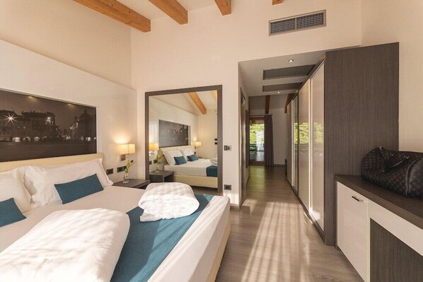 A hotel room with a large bed, a desk, a mirror, and a view of the outdoors. - Albermonaco (Trento)