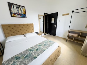 Een slaapkamer met een groot bed, een kledingkast, een deur en een schilderij aan de muur.
