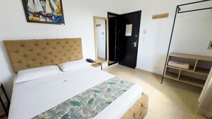 Un dormitorio con una cama grande, cabecera, mesita de noche, armario, espejo y un cuadro en la pared.
