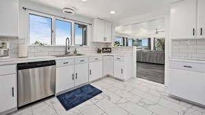 A modern kitchen with white cabinets, a dishwasher, and a large window. - Rimview Haven: Hot Tub, Waterfall Trail & Golf! (Jerome)