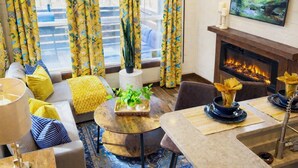 A cozy living room with a fireplace, yellow curtains, a sofa, and a dining area.