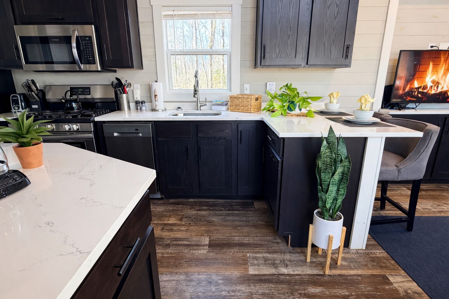 Una cocina moderna con armarios oscuros, una encimera blanca y una estufa integrada.