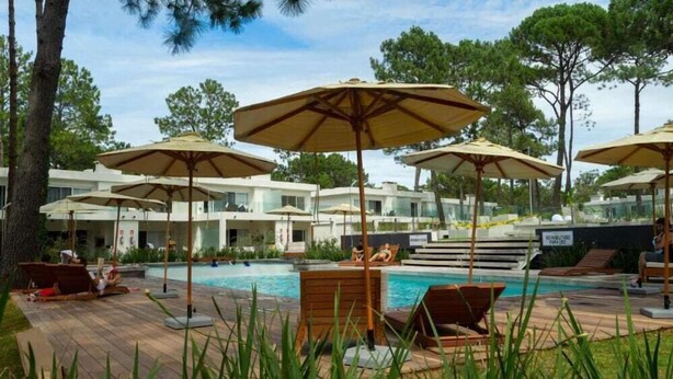 A pool area with lounge chairs and umbrellas, surrounded by buildings with a modern design. - Solanas Punta Del Este Spa Resort (Punta del Este)