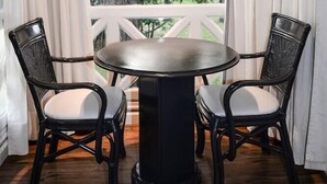 A dining area with a round table and two chairs, a white railing, and a view of trees and a white fence. - Solanas Punta Del Este Spa Resort (Punta del Este)
