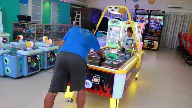 Eine Spielhalle mit verschiedenen Spielautomaten, darunter ein Tischtennistisch und Krallenautomaten.