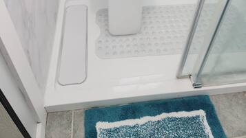 Une salle de bain avec douche, toilettes et porte en verre.