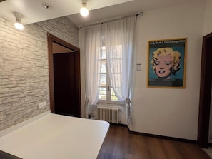A room with a stone wall, a white bed, a radiator, and a poster on the wall. - Logicasa Old City Como (Como)