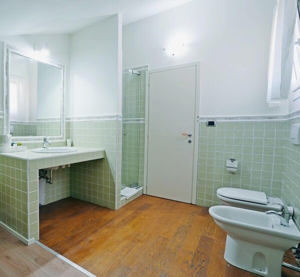 A bathroom with a sink, mirror, toilet, bidet, and a shower area. - Avanguardia Suite Ferrara (Ferrara)