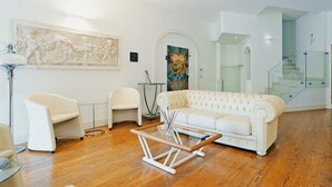 A spacious living room with a white sofa, a glass coffee table, and a modern staircase. - Avanguardia Suite Ferrara (Ferrara)
