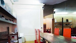 A dining area with a long wooden table, red chairs, and a black mat on the floor. There are shelves with various items on the left side. - Avanguardia Suite Ferrara (Ferrara)