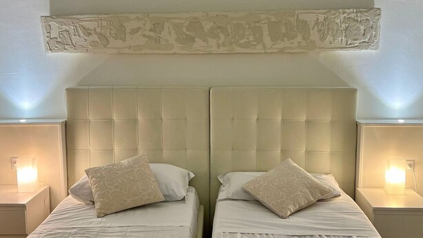 A double room with two beds, each with a headboard, bedside tables, and lamps. - Avanguardia Suite Ferrara (Ferrara)
