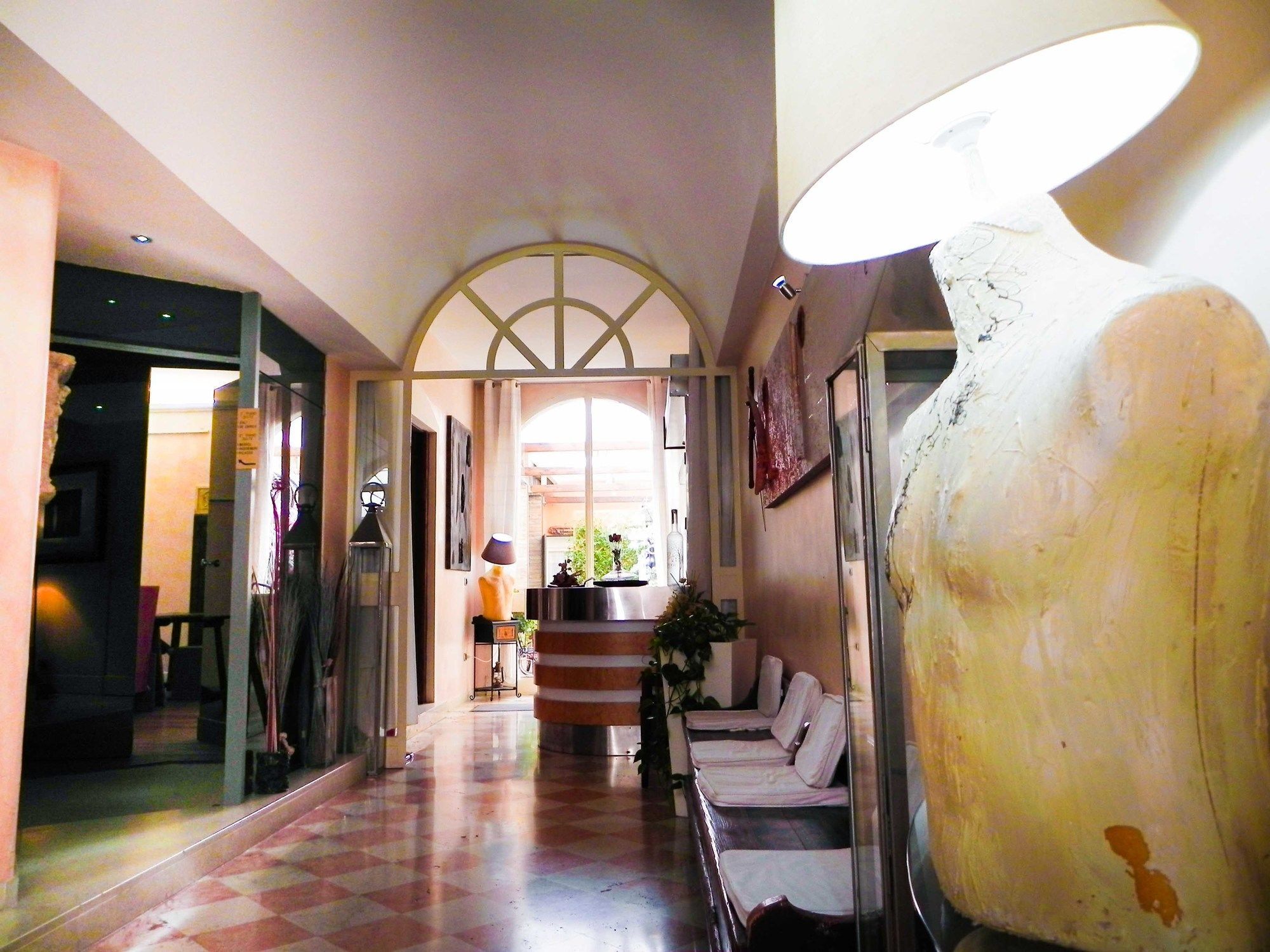 Una hall d'albergo con pavimento a scacchi, una reception e un vaso grande.