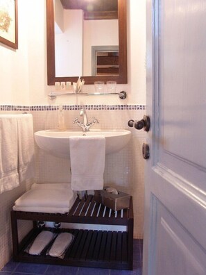 A bathroom with a sink, mirror, towel rack, and a small shelf with toiletries. - Agriturismo Villanova (Levanto)