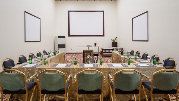 Une salle de conférence équipée d’une longue table, de chaises et d’un écran de projection.