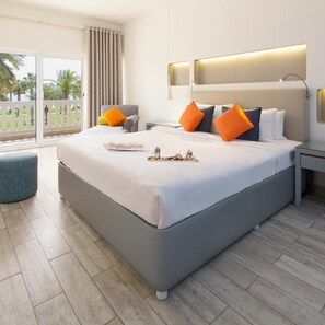 Una habitación de hotel moderna con una cama grande, una mesita de noche, una zona de estar y un balcón con vistas.
