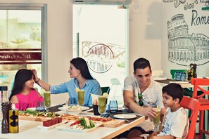 Eine Familie speist in einem Restaurant mit Blick auf die Stadt, darunter ein bekanntes Wahrzeichen.