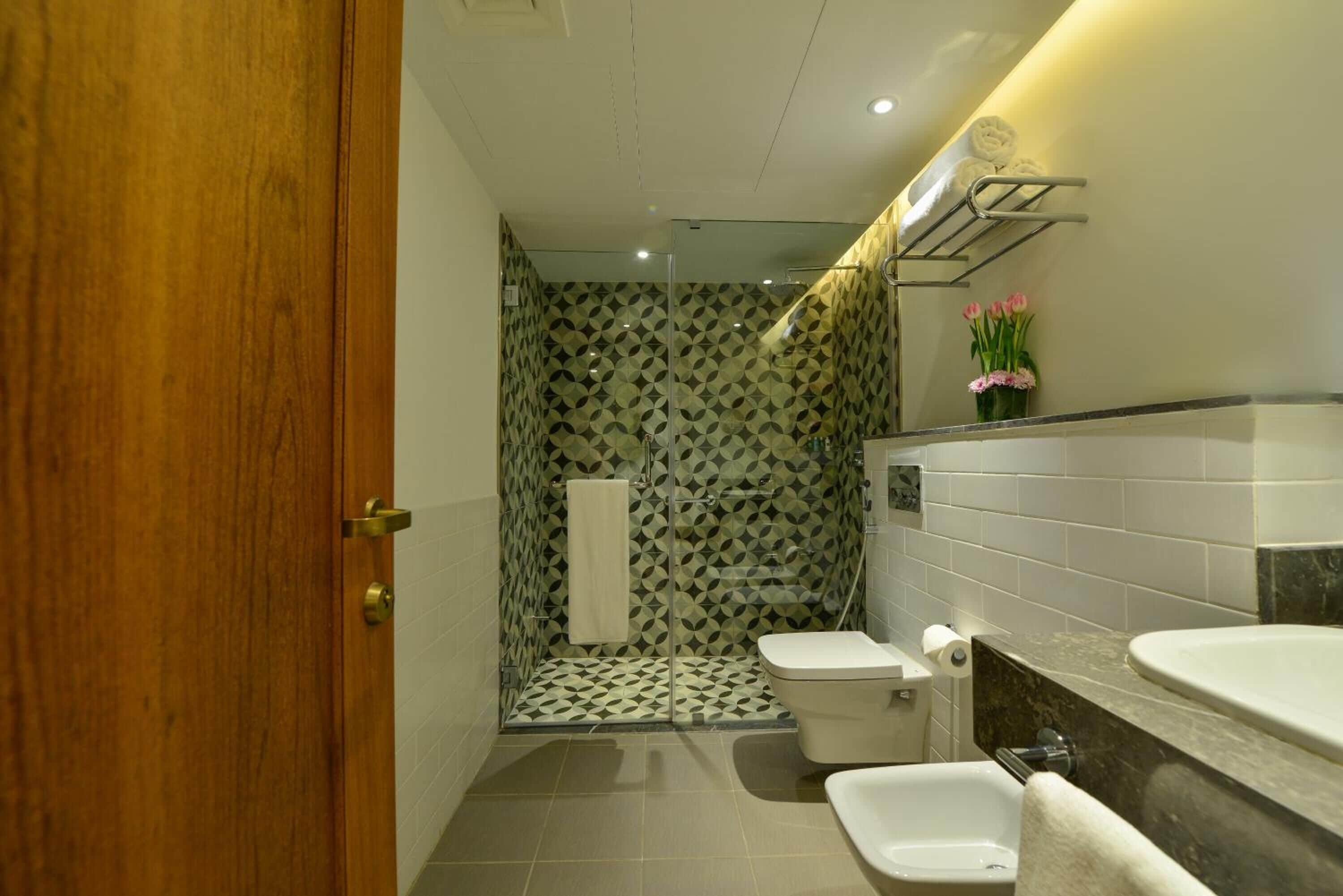 A bathroom with a shower, toilet, bidet, and a sink.