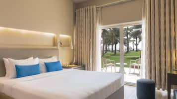 A hotel room with a large bed, a desk, and a view of a green landscape.