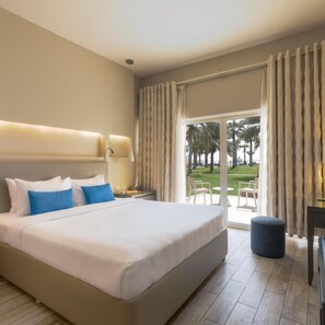 Een hotelkamer met een groot bed, een bureau en uitzicht op een groen landschap.