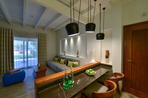 A modern living room with a sofa, a coffee table, and a dining area with chairs and a marble countertop. - Sealine Beach, a Murwab Resort (Mesaieed)