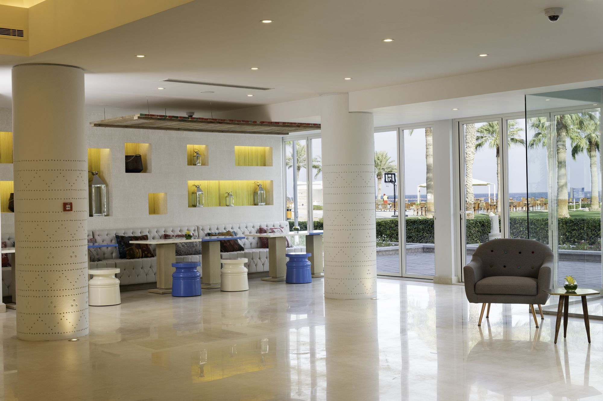 Eine moderne Lobby mit Sitzgelegenheit, einer Rezeption und großen Fenstern mit Blick ins Freie.