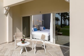 Een balkon met een bed, twee stoelen en een tafel.