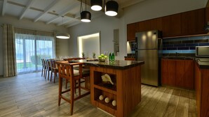 Uma cozinha moderna com armários de madeira, uma geladeira de aço inoxidável e um espaço de jantar com mesa e cadeiras.