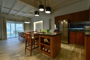 Een moderne keuken met houten kastjes, een roestvrijstalen koelkast en een eethoek met een tafel en stoelen.