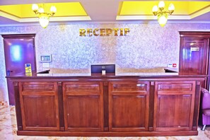 A reception desk with a 'RECEPTION' sign, a computer, and a telephone.