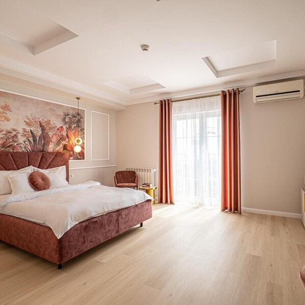 Un dormitorio con una cama grande, una silla, un radiador y una ventana con cortinas.