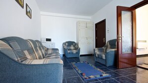 A living room with a sofa, two armchairs, a small table with a microwave, and a door with frosted glass. - Central Mamaia (Constanta)