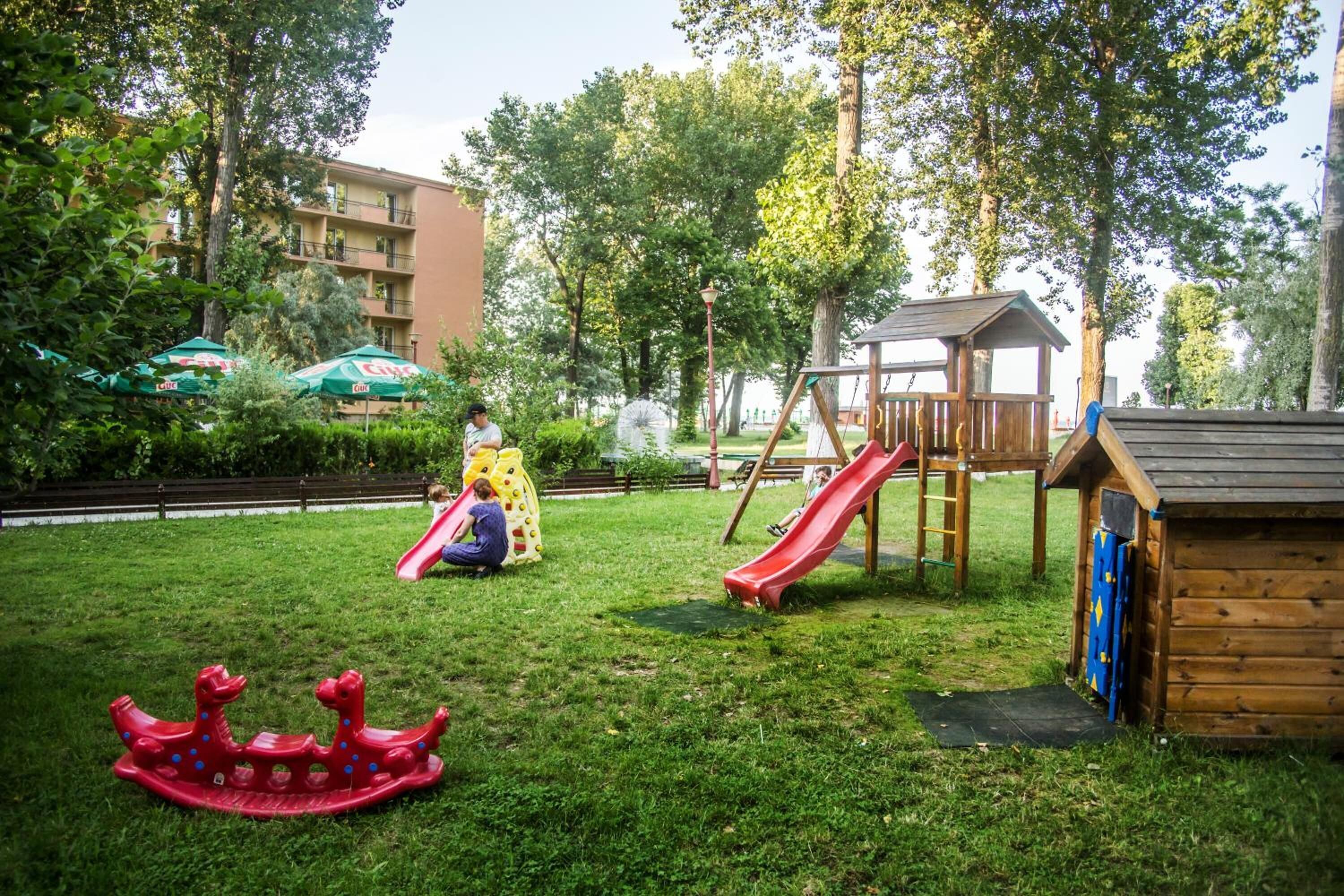 A playground with a slide, a swing set, and a small wooden structure.