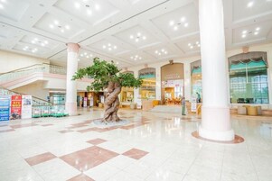 Un amplio atrio con un árbol artificial en el centro, varios niveles y una tienda 'FAMILIAR'.