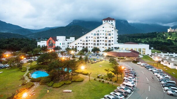 A hotel with a prominent white building, a swimming pool, and a parking lot. - Ilsung Seorak Oncheo Condo and Resort (Goseong)