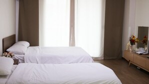A hotel room with two beds, a wooden dresser, a mirror, and a window with curtains. - Ilsung Seorak Oncheo Condo and Resort (Goseong)