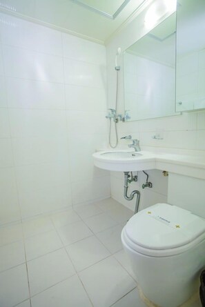 Un baño con lavamanos, espejo y retrete blancos.