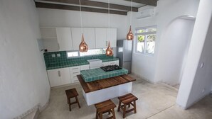 A kitchen with a central island, white cabinets, green tiles, and copper pendant lights. - Bahia Mar Beach House (Vilanculos)