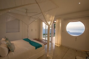 Een slaapkamer met een groot bed, een raam met uitzicht en een plafondventilator.
