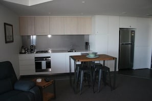 Eine moderne Küche mit weißen Schränken, einem Edelstahl-Kühlschrank und einer Essecke mit Barhocker.